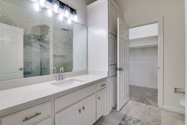 Bathroom with a marble finish shower, vanity, a spacious closet, marble look tiles, and baseboards | Image 12