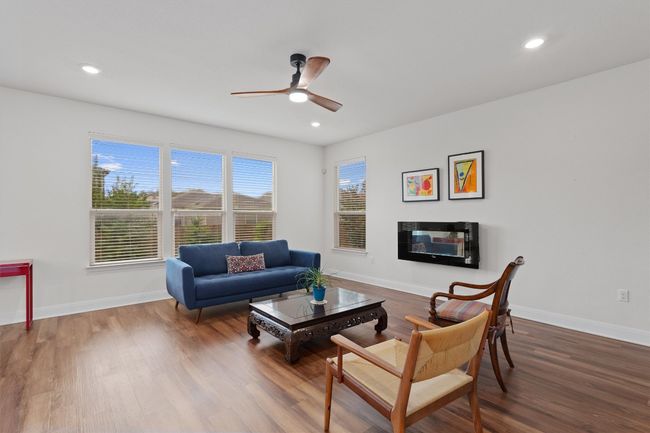 Living room featuring a ceiling fan, wood finished floors, recessed lighting, and a glass covered fireplace | Image 6
