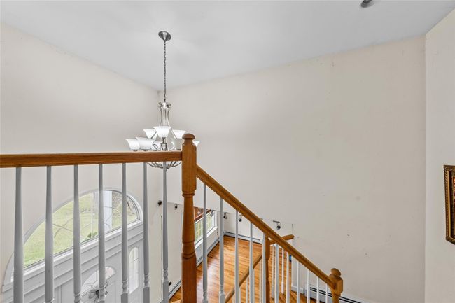 Staircase featuring baseboard heating, wood finished floors, and a notable chandelier | Image 21