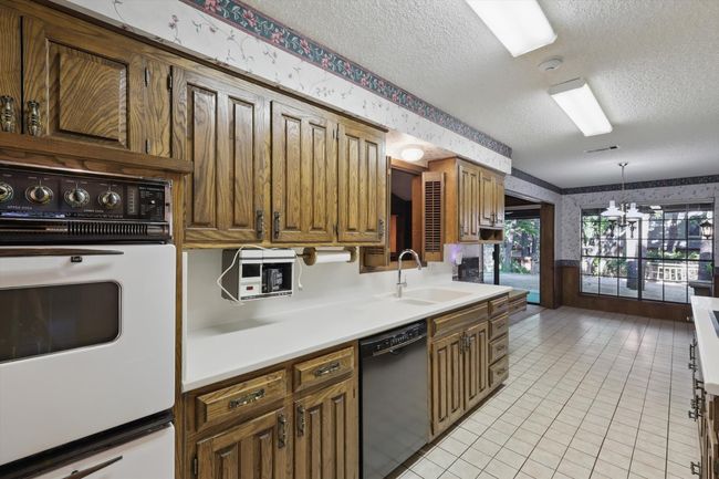 Kitchen with dishwasher, white oven, a textured ceiling, and wallpapered walls | Image 8
