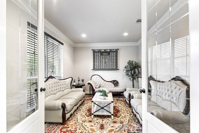 As you walk in, to your left, you'll find French doors that lead into a private home office. This space is enhanced with recessed lighting, crown molding, and beautiful wood flooring, creating a sophisticated atmosphere. A large window offers serene views of the front yard, allowing natural light to brighten the room. While currently being used as a cozy seating room, this versatile area can easily serve as an office or a space tailored to your needs. The combination of style and function makes this room a | Image 10