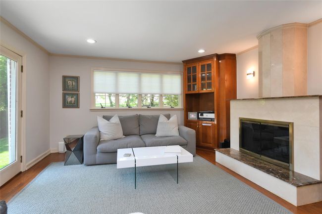 Living room featuring ornamental molding, a healthy amount of sunlight, a high end fireplace, and wood finished floors | Image 9