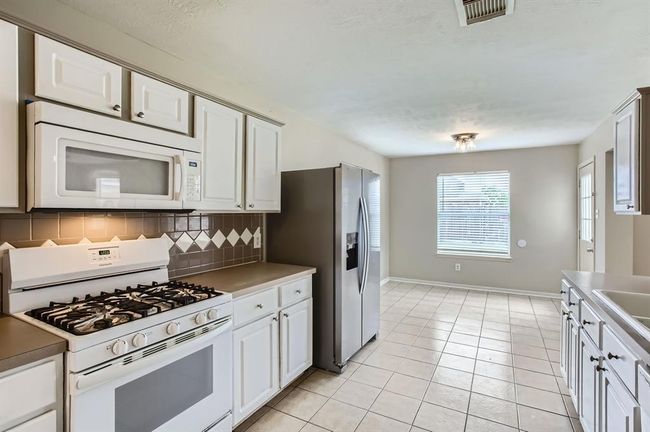 Kitchen offers plenty of cabinetry and counterspace. | Image 14