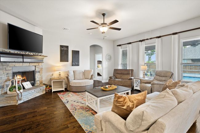 Living room with arched walkways, a fireplace, visible vents, dark wood-type flooring, and ceiling fan | Image 12