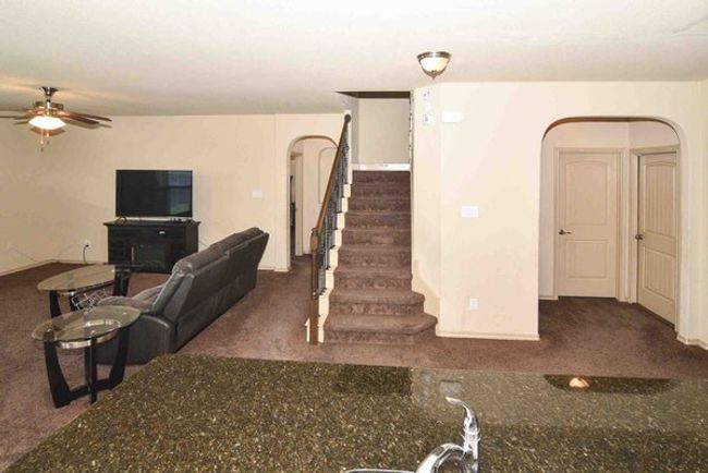 Living area with carpet, a ceiling fan, and stairs | Image 10
