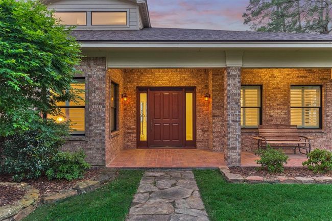 The original 4' x 7' solid wood door was carefully refinished and preserved, adding a distinctive, character-rich touch to the home. The covered front entry is enhanced by classic brick flooring and beautifully landscaped beds bordered with stone edging. | Image 7