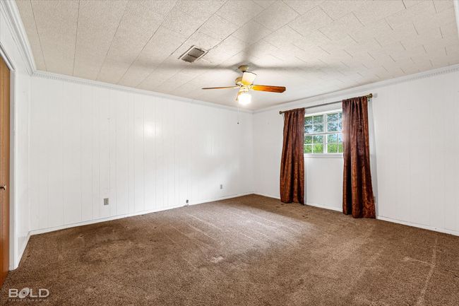 Spare room with a ceiling fan, carpet floors, crown molding, and wood walls | Image 23