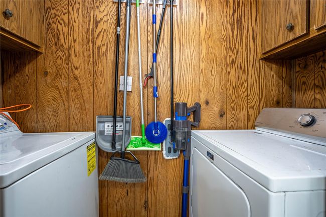 Laundry area featuring cabinet space, independent washer and dryer, and wood walls | Image 15