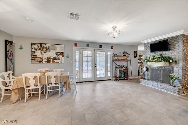Dining area featuring french doors, a brick fireplace, and a chandelier | Image 39