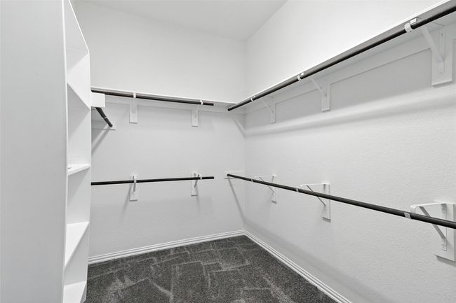Walk in closet featuring dark carpet | Image 32