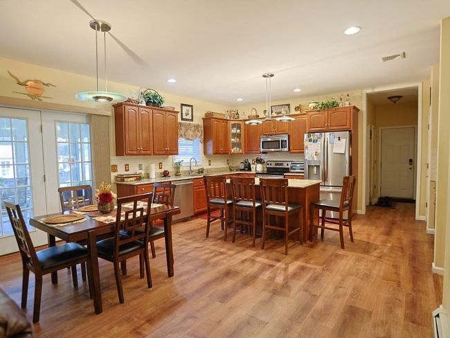 Dining area featuring light wood-style flooring, visible vents, baseboards, recessed lighting, and a baseboard heating unit | Image 6