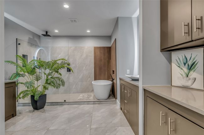 Master suite bath featuring a walk in shower, a freestanding bath, vanity, marble look tile flooring, and recessed lighting | Image 20