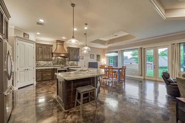 The center island is highlighted by glass pendants and provides additional seating. | Image 20