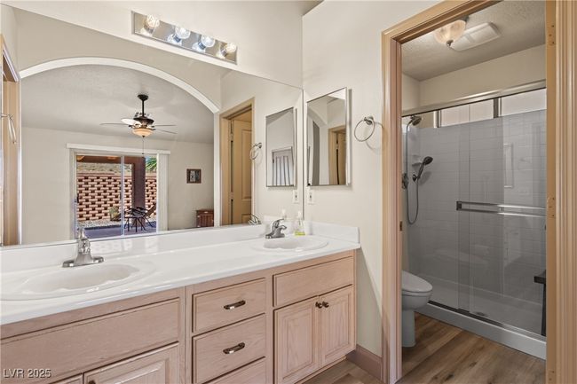 Bathroom featuring a stall shower, double vanity, wood finished floors, and a ceiling fan | Image 36
