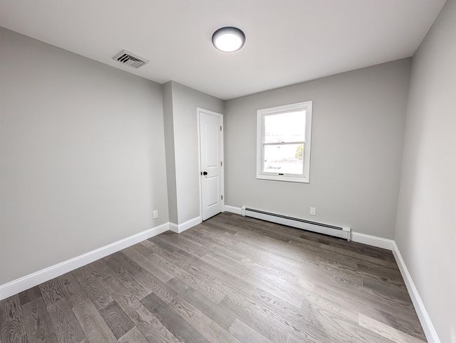 Empty room with a baseboard heating unit, visible vents, baseboards, and wood finished floors | Image 14