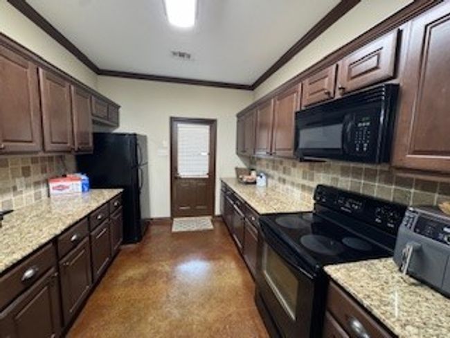 Kitchen featuring range, ornamental molding, fridge, dark brown cabinets, and backsplash | Image 23