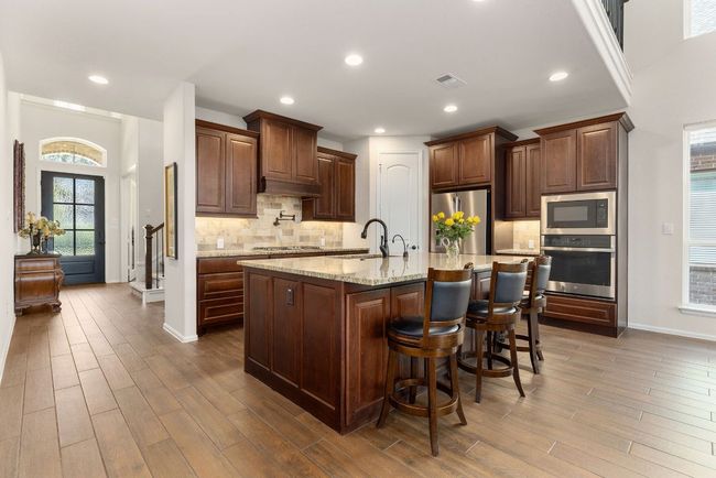 Kitchen with plenty of natural light, appliances with stainless steel finishes, dark wood-style floors, light stone counters, and recessed lighting | Image 7