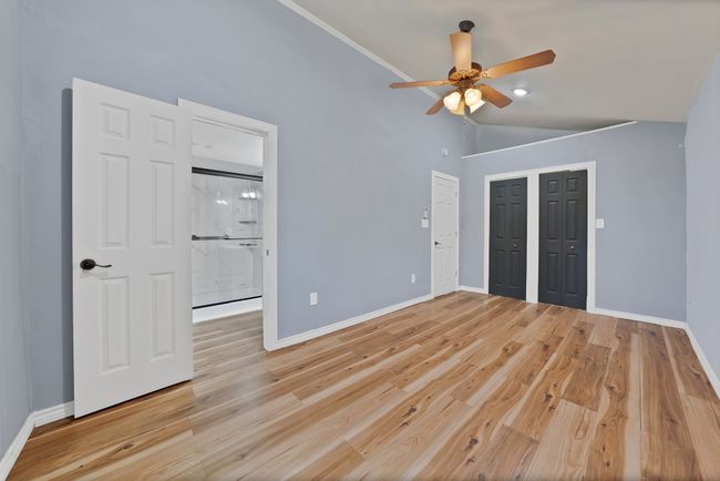 Unfurnished bedroom with vaulted ceiling, light wood-style flooring, ceiling fan, and ensuite bath | Image 8
