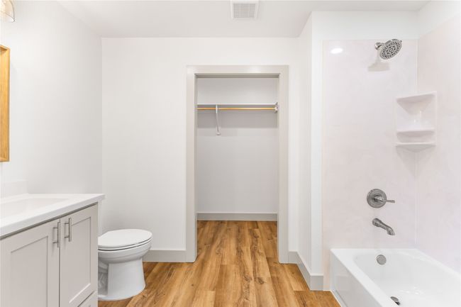 Full bathroom featuring wood finished floors, washtub / shower combination, toilet, vanity, and a walk in closet | Image 19