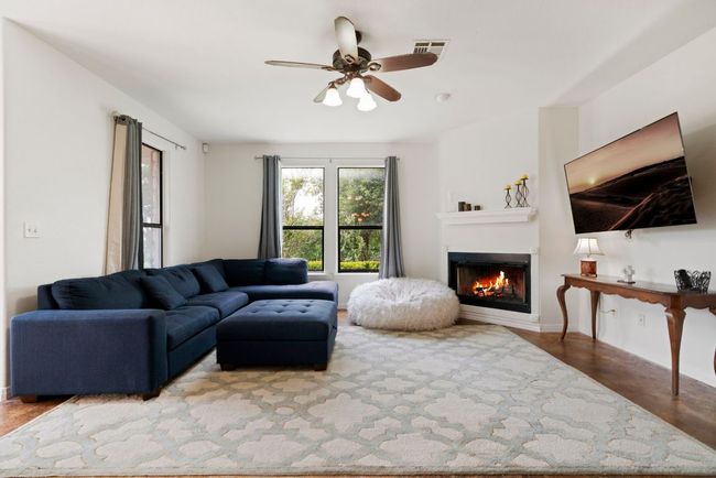 The living room centers around a striking wood-burning fireplace, creating a warm and inviting atmosphere for everyday living and entertaining. | Image 4