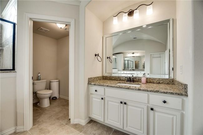 Bathroom featuring toilet, vanity, tile patterned flooring, baseboards, and lofted ceiling | Image 24