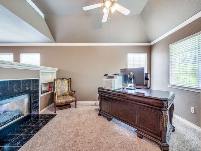 Carpeted home office featuring lofted ceiling, plenty of natural light, ceiling fan, and a tile fireplace | Image 19