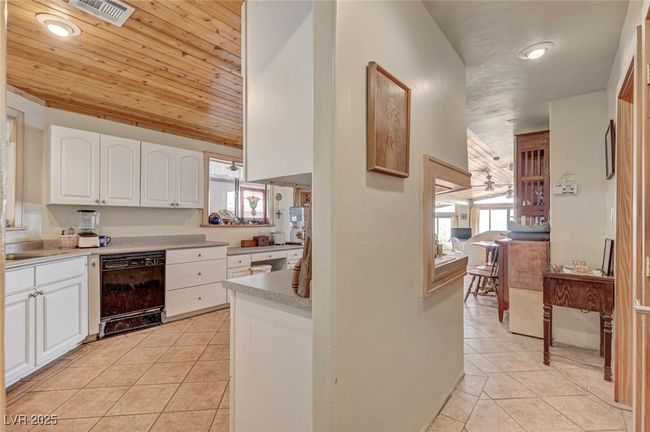 Kitchen with light tile patterned floors, wooden ceiling, dishwasher, white cabinets, and recessed lighting | Image 33
