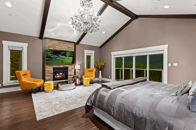 Bedroom featuring a chandelier, a fireplace, wood finished floors, baseboards, and beamed ceiling | Image 20