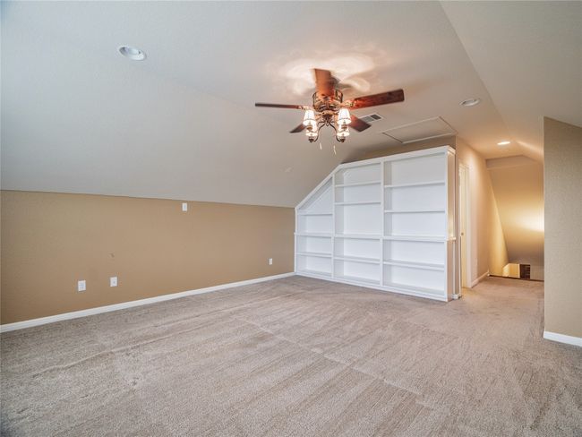 Additional living space featuring a ceiling fan, built in features, vaulted ceiling, light colored carpet, and recessed lighting | Image 37