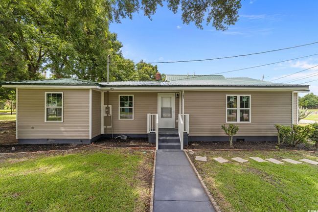 View of front of property with crawl space, a front yard, and a metal roof | Image 4