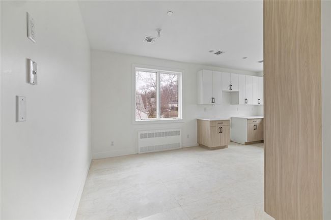 Unfurnished living room featuring radiator heating unit, visible vents, and baseboards | Image 15