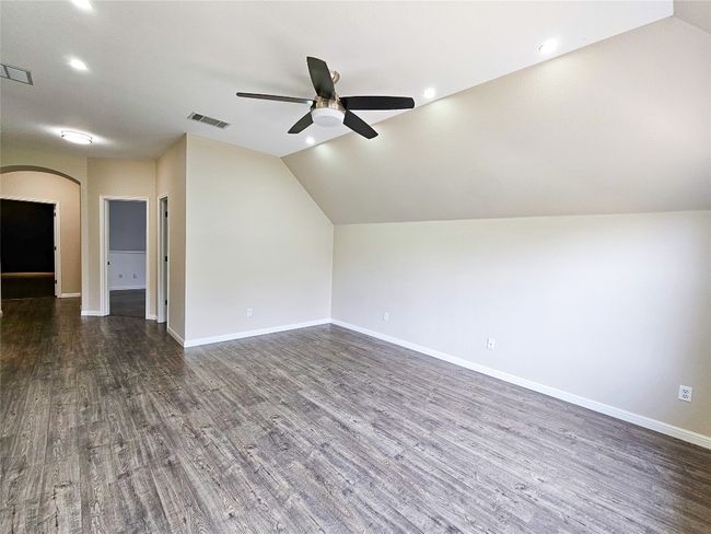 Bonus room featuring ceiling fan, arched walkways, dark wood-type flooring, baseboards, and vaulted ceiling | Image 18
