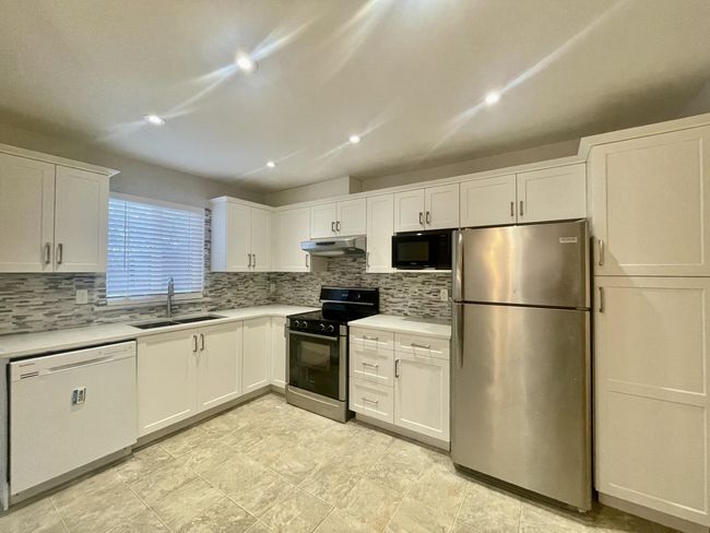 Kitchen with electric range oven, freestanding refrigerator, a sink, dishwasher, and black microwave | Image 34