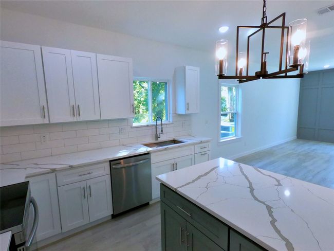 Kitchen with stainless steel dishwasher, light wood-style floors, visible vents, and a sink | Image 8