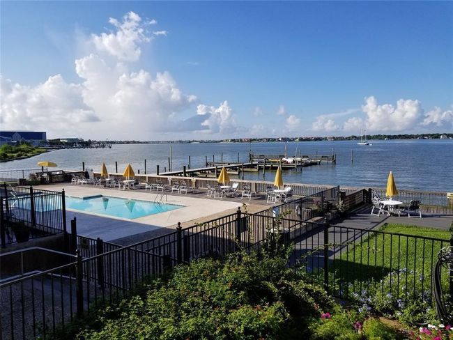 This photo showcases a waterfront property with a pool, surrounded by a spacious deck and seating area. It features a scenic view of the water and a dock, offering a serene and inviting atmosphere. | Image 23