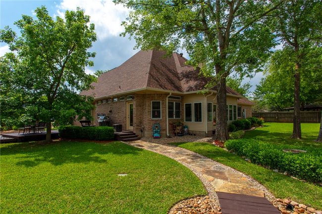 Rear view of property featuring roof with shingles, fence, a wooden deck, brick siding, and a lawn | Image 33