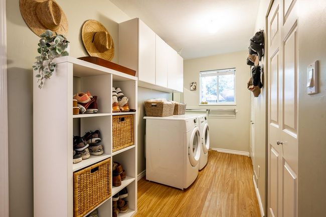 Laundry room with light wood-type flooring, washing machine and dryer, and cabinet space | Image 20