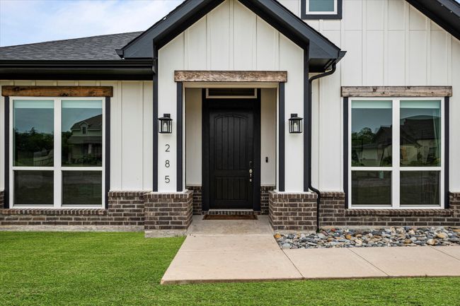 Property entrance with roof with shingles, brick siding, a yard, and board and batten siding | Image 4