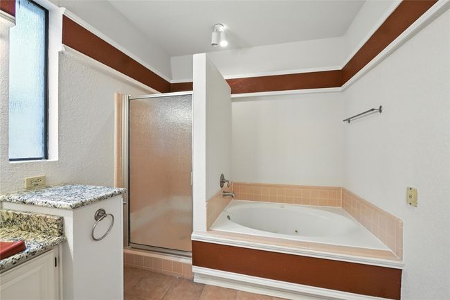 Bathroom with a stall shower, a jetted tub, vanity, and tile patterned floors | Image 23