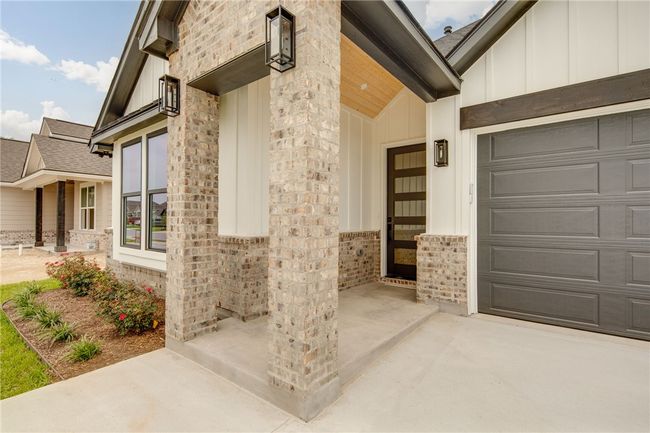 View of exterior entry featuring board and batten siding, an attached garage, driveway, and brick siding | Image 4