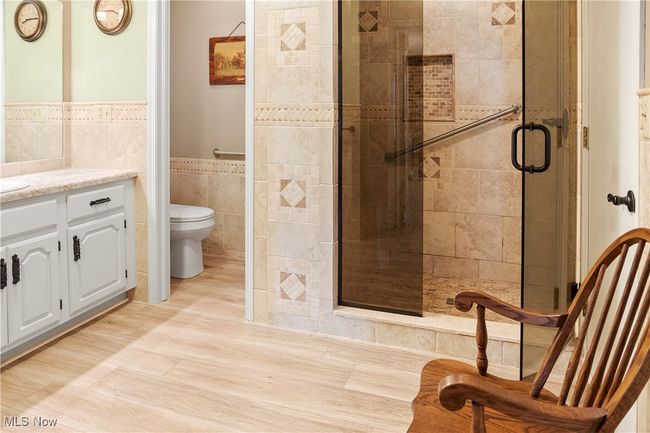 Full bathroom with a shower stall, toilet, vanity, tile walls, and wainscoting | Image 23