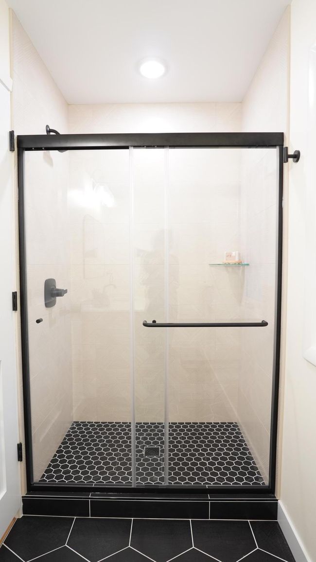 The large hall bath shower features custom tile work in a modern and fun design and matte black plumbing fixtures. | Image 22