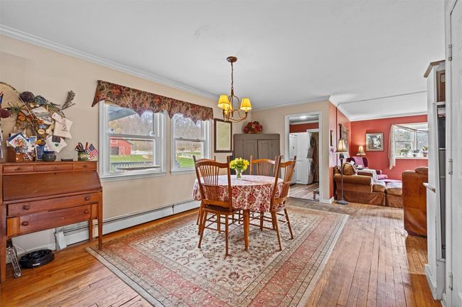 Dining area featuring ornamental molding, hardwood / wood-style floors, an inviting chandelier, and a baseboard heating unit | Image 9
