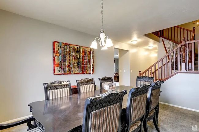 Carpeted dining room featuring baseboards, stairs, and a chandelier | Image 7