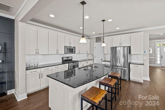 Bright kitchen with oversized island, stainless steel appliances & walk-in pantry. | Image 11