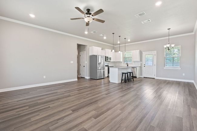 Living area featuring ceiling fan, a chandelier, dark wood-style flooring, recessed lighting, and crown molding | Image 4