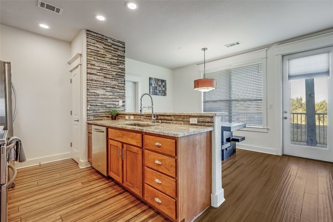 Kitchen with stainless steel dishwasher, visible vents, brown cabinetry, and a sink | Image 9