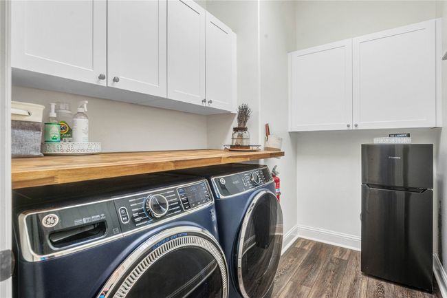 Laundry room with independent washer and dryer, dark wood-style flooring, and cabinet space | Image 17
