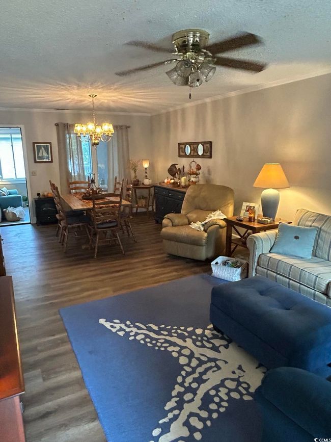 Living room featuring a chandelier, wood finished floors, a textured ceiling, a ceiling fan, and crown molding | Image 12