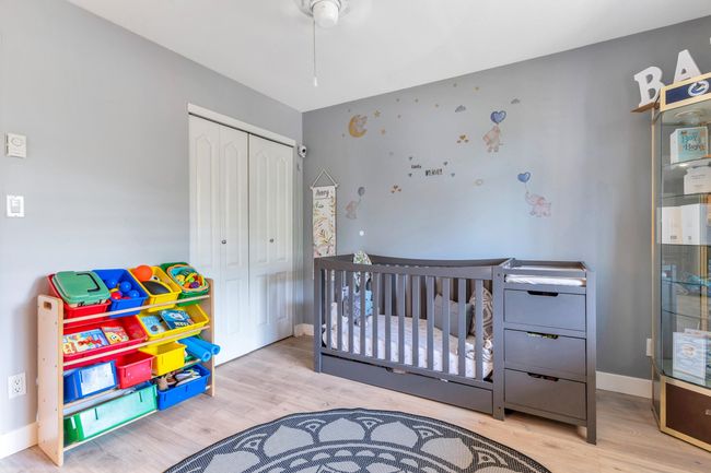 Bedroom featuring a closet, a crib, baseboards, and wood finished floors | Image 22